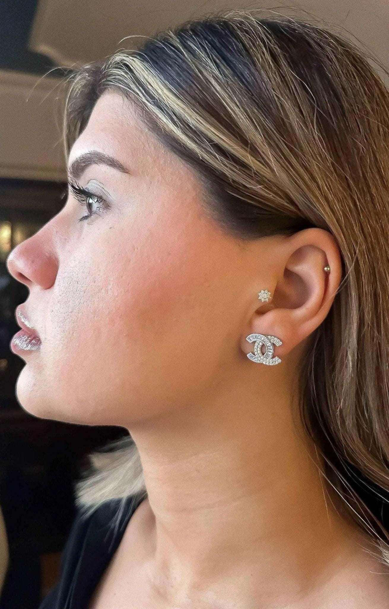 Close-up of a woman wearing authentic Chanel stud earrings in 925 sterling silver with baguette white zircon stones.