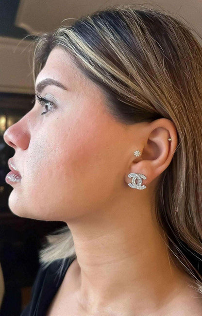 Close-up of a woman wearing authentic Chanel stud earrings in 925 sterling silver with baguette white zircon stones.